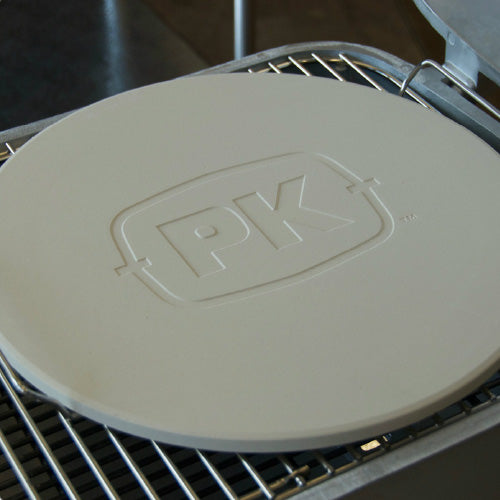 Premium round Firesmiths cast iron pizza stone with embossed PK logo, placed on a cooking grate for baking crispy pizzas, artisan bread, and other high-heat barbecue dishes.