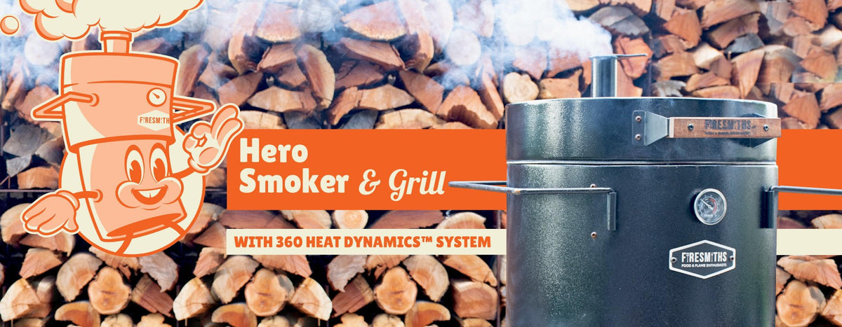 Promotional Firesmiths Hero Smoker & Grill banner featuring the Hero Smoker, the Smithy mascot, stacked firewood background, and the 360° Heat Dynamics™ System for authentic wood-fired smoking and grilling.