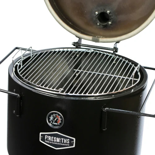 Firesmiths Hero Smoker & Grill with the lid open, showcasing the heavy-duty stainless steel circular cooking grate with integrated lifting handles for even heat distribution and premium wood-fired grilling and smoking.