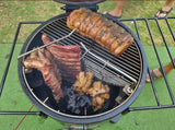 Firesmiths Hero Smoker & Grill in use with pork belly roasting on the cooking grate while ribs and chicken hang below, showcasing the versatile combination grilling and wood-fired smoking system.