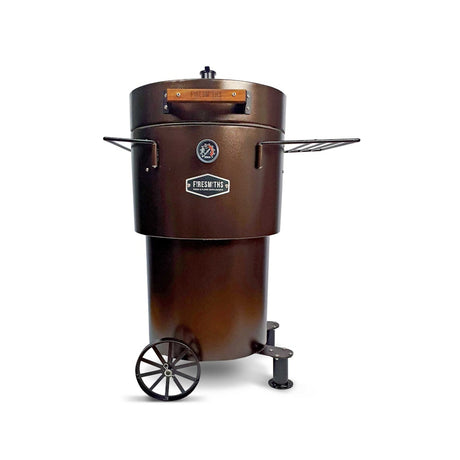 Firesmiths Hero Smoker & Grill in the Bronze Edition featuring a built-in temperature gauge, adjustable chimney, wooden handle, dual side shelves, and a wheeled base for premium wood-fired smoking and grilling.