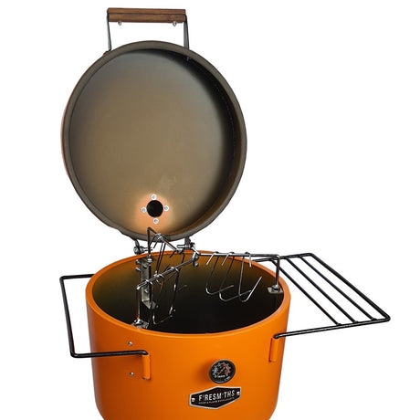 Firesmiths Hero Smoker & Grill in the Burnt Orange finish with the lid open, showcasing the stainless steel hanging rack system, meat hooks, dual side shelves, and built-in temperature gauge for versatile wood-fired smoking.