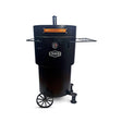 Matte black Firesmiths Hero Smoker & Grill with a built-in temperature gauge, chimney stack, wooden handle, dual side preparation shelves, transport wheels, and heavy-duty steel construction for premium wood-fired smoking and grilling.