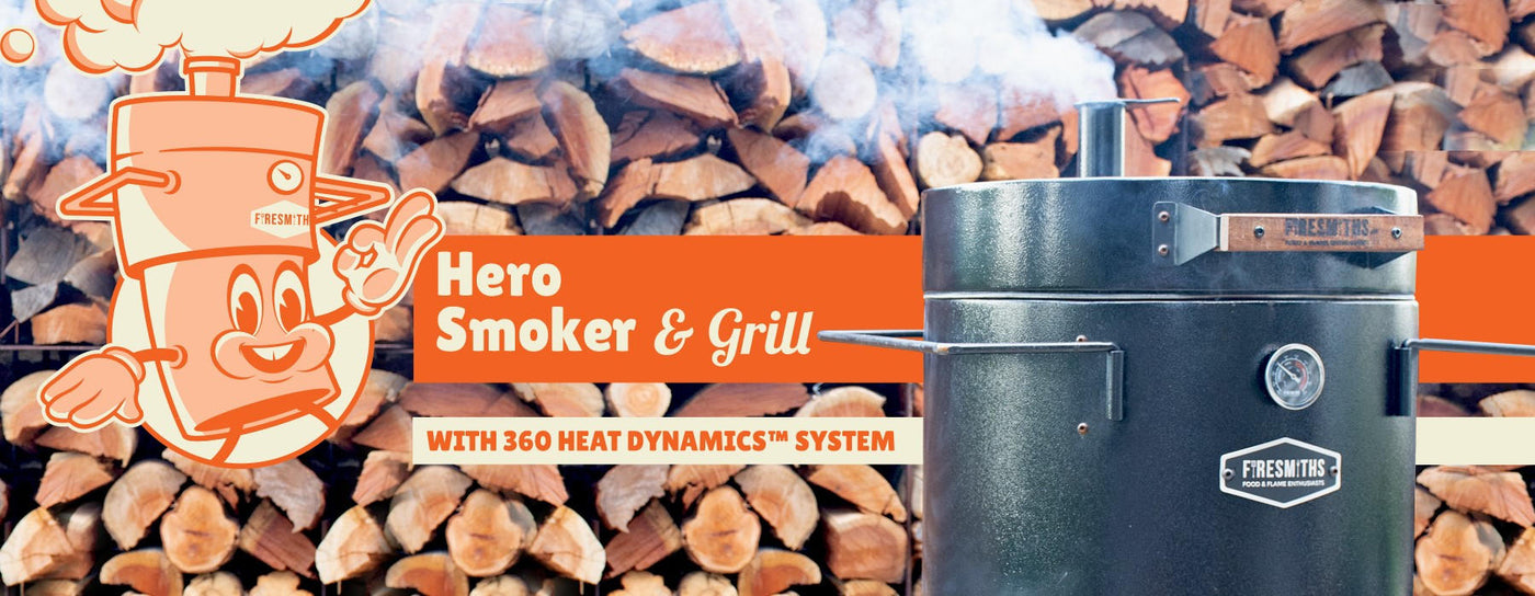 Promotional Firesmiths Hero Smoker & Grill banner featuring the Hero Smoker, the Smithy mascot, stacked firewood background, and the 360° Heat Dynamics™ System for authentic wood-fired smoking and grilling.