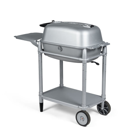 Firesmiths PK360 Silver charcoal grill mounted on a heavy-duty rolling cart with a side shelf, lower storage shelf, cast aluminum body, and precision airflow controls for premium grilling and smoking.