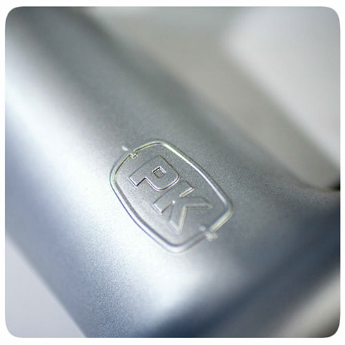 Close-up of the embossed PK logo on the premium cast aluminum body of a Firesmiths PK Series charcoal grill, highlighting its durable construction and high-quality craftsmanship.