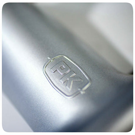 Close-up of the embossed PK logo on the premium cast aluminum body of a Firesmiths PK Series charcoal grill, highlighting its durable construction and high-quality craftsmanship.